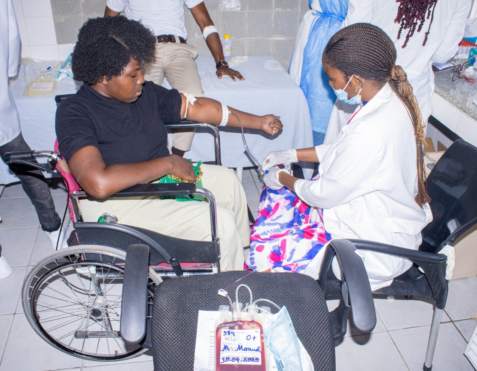 Enfermeira do ISPRL a acompanhar dadora de sangue em cadeira de rodas durante campanha de doação
