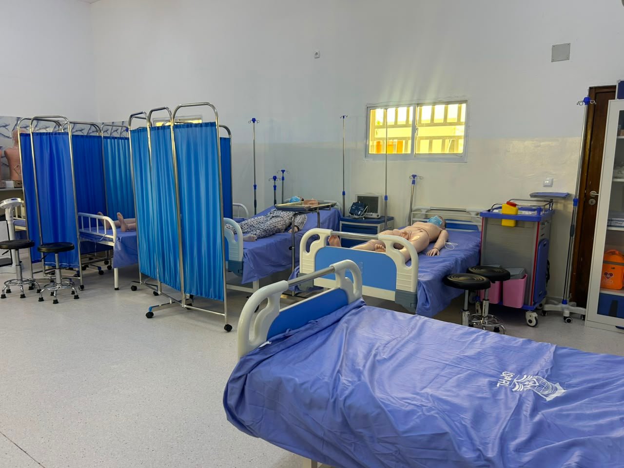 Sala de prática de saúde do ISPRL com camas hospitalares e manequins de simulação clínica
